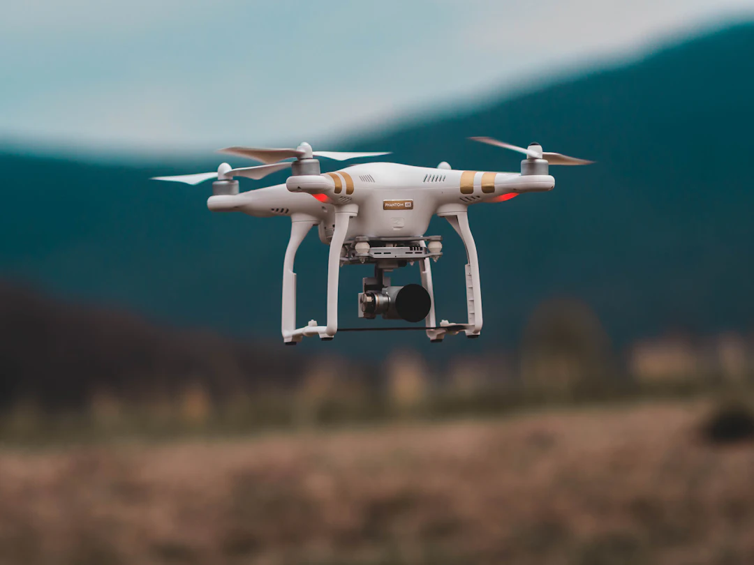 Drone en vol stationnaire au-dessus d’un champ, collines en arrière-plan
